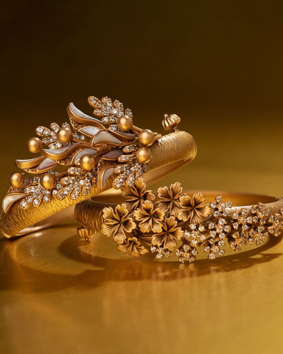 Blossom Pair — Two bands, two gardens — one in mother-of-pearl petals, one in matte gold flowers scattered with small stones.